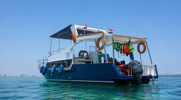Das Boot von hinten vor einer Sandbank, mit Rettungswesten und Schnorchelausrüstung an Deck