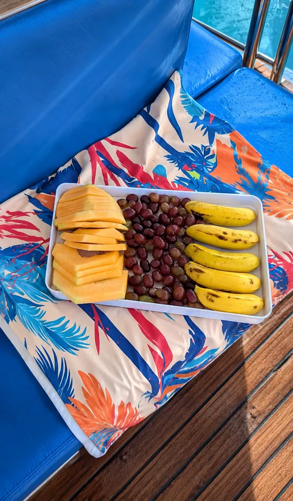 Frisch aufgeschnittenes Obst – Melone, Weintrauben und Bananen – auf einem Tablett an Deck